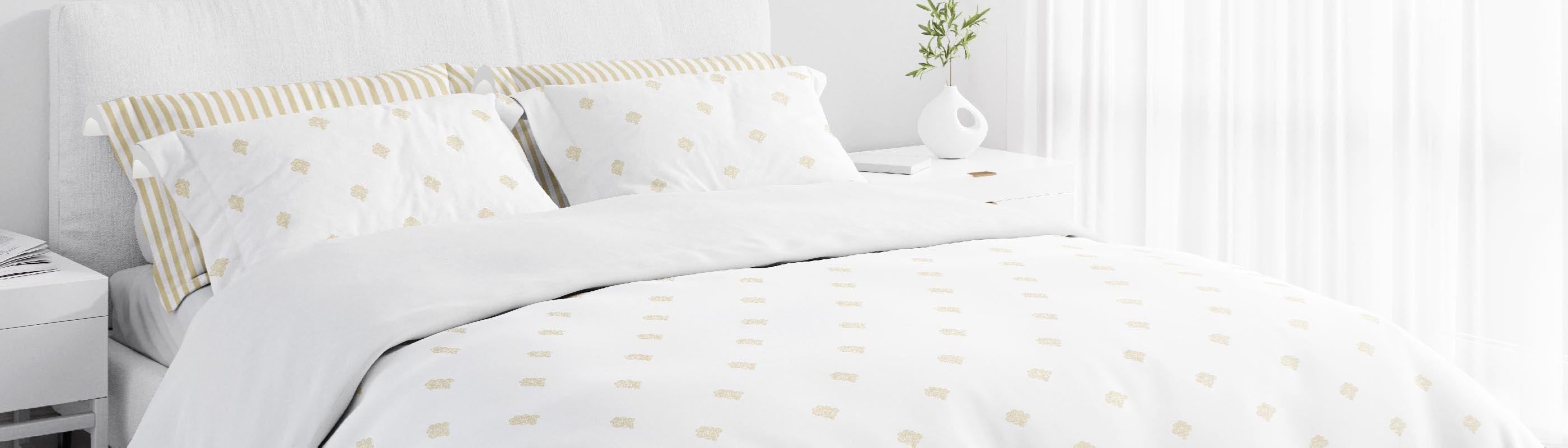 White bedding set with gold accents on a bed in a bedroom.