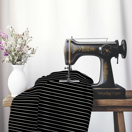 Spun Polyester Fabric with Fine Pale Cream Stripes on Black, FASP-1013-152, on an antique sewing machine sitting on a desk with vase of beautiful flowers.