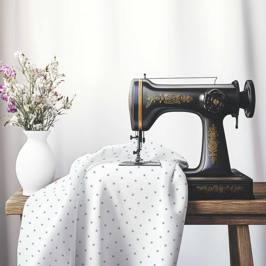 White Spun Polyester Fabric with Blue Diamonds, FASP-1231-101, on an antique sewing machine sitting on a desk with vase of beautiful flowers.