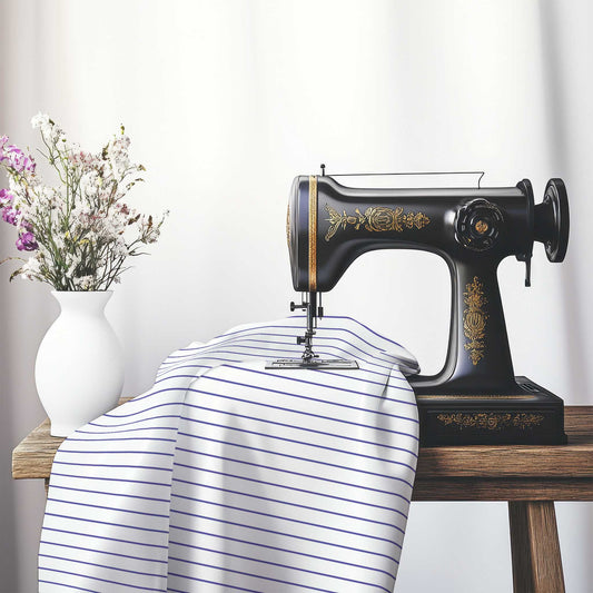 White Spun Polyester Fabric with Fine Purple Stripes, FASP-1300-151, on an antique sewing machine sitting on a desk with vase of beautiful flowers.