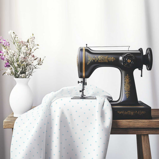 White Spun Polyester Fabric with Blue Diamonds, FASP-1370-101, on an antique sewing machine sitting on a desk with vase of beautiful flowers.