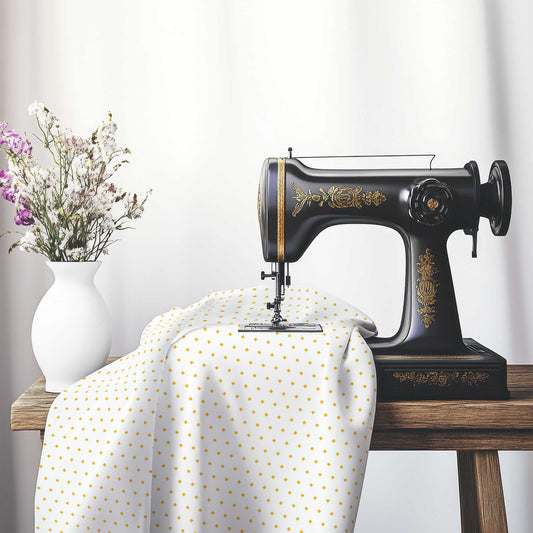White Spun Polyester Fabric with Fine Yellow-Orange Diamonds, FASP-1390-111, on an antique sewing machine sitting on a desk with vase of beautiful flowers.
