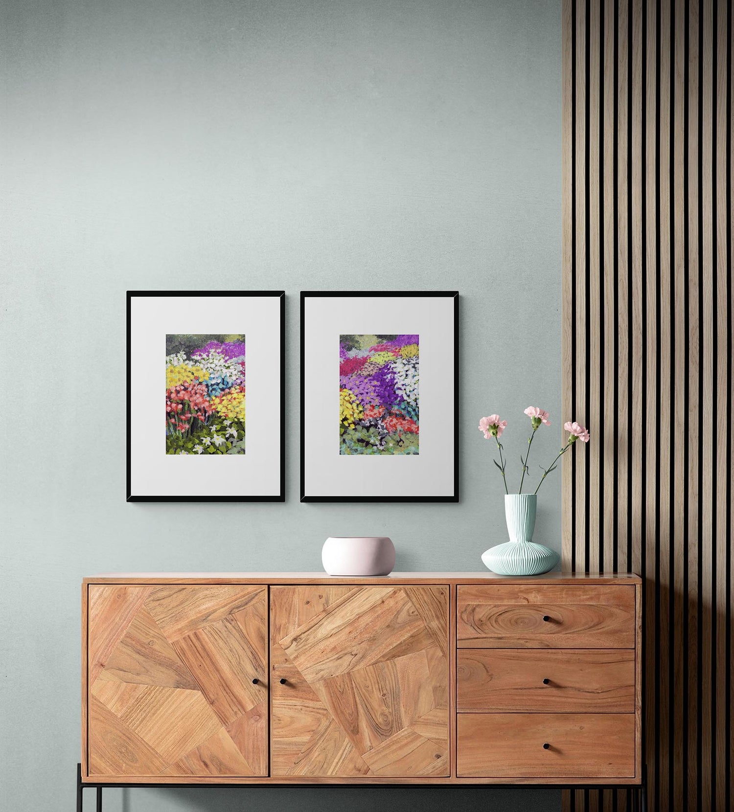Wooden sideboard with two framed floral prints on a gray-blue wall.